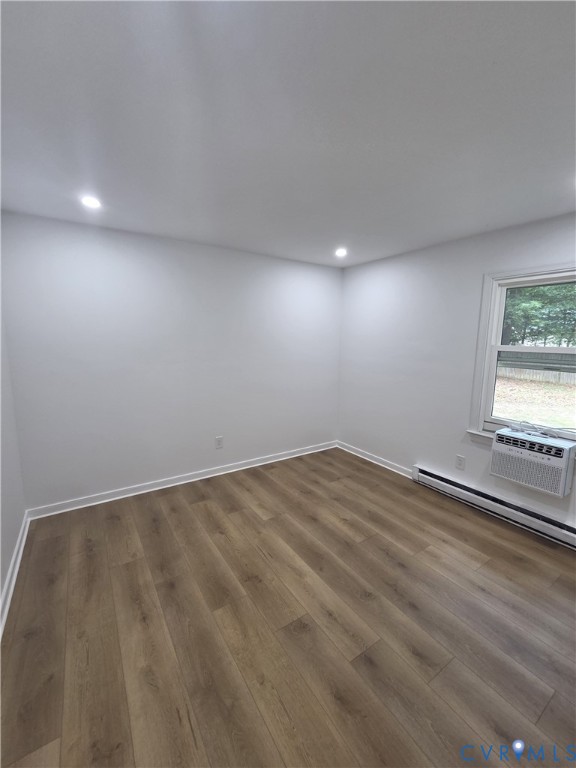 1st bedroom, 1st floor. Recessed lighting, wood-finish flooring, white walls, window, and baseboard heating