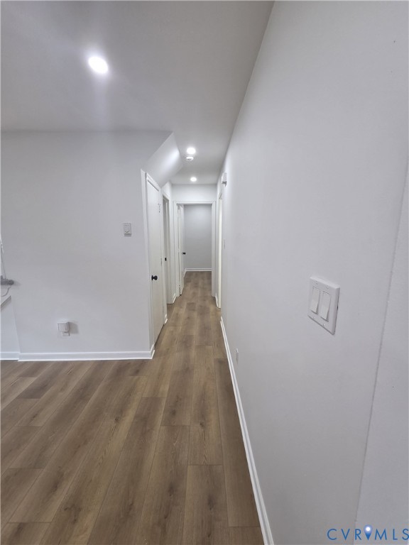 Hallway featuring wood-finish flooring, recessed ceiling lighting, and white interior doors