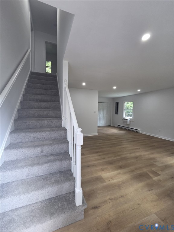 Light gray wall paint, recessed ceiling lighting, light wood-finish flooring, white painted stair railing, and gray carpeted stairs Light gray wall paint, recessed ceiling lighting, light wood-finish flooring, white painted stair railing, and gray carpeted stairs