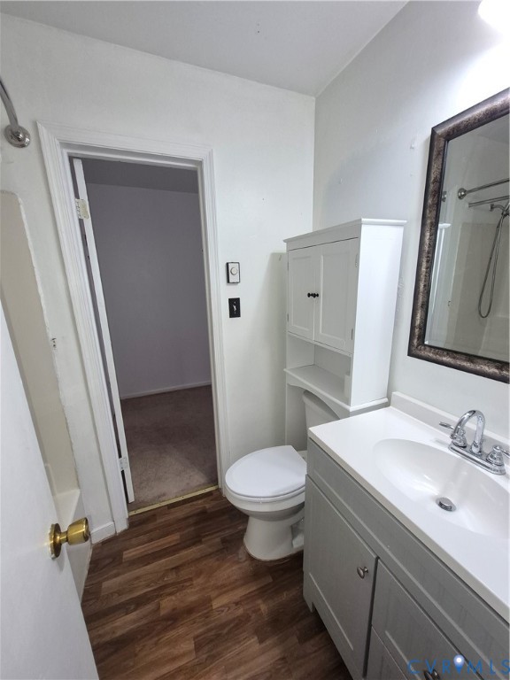 Wood-finish flooring, white vanity with integrated sink, white built-in storage cabinet, and a framed mirror