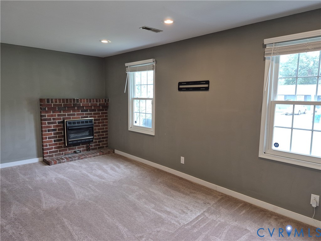 Wall-to-wall carpeting, recessed ceiling lighting, and a brick fireplace