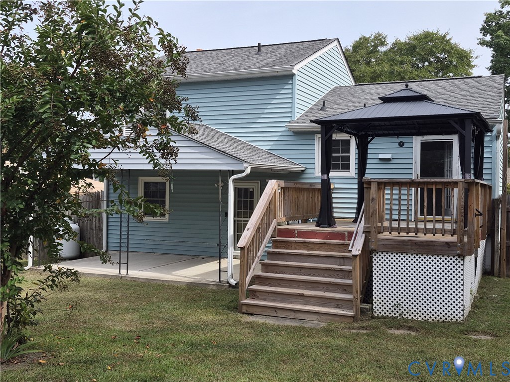 Expansive backyard featuring a multi-level wood deck, a covered gazebo, a concrete patio, and blue siding