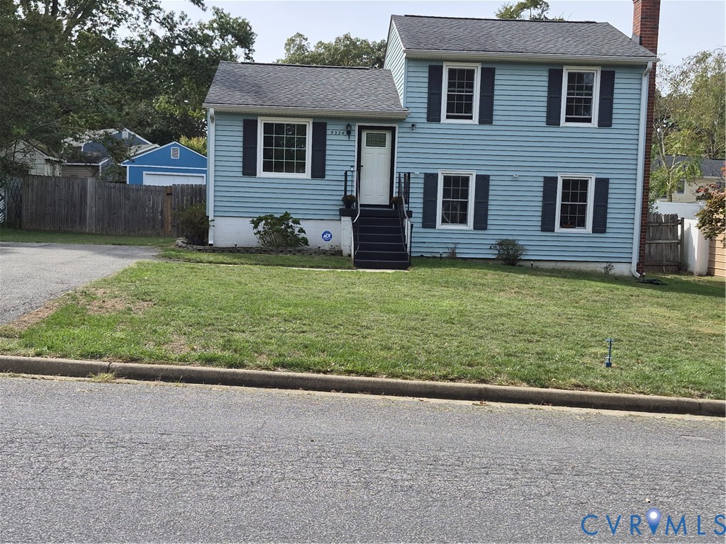 Two-story residence featuring light blue siding, dark shutters, and a front entry with dark stairs and white railing