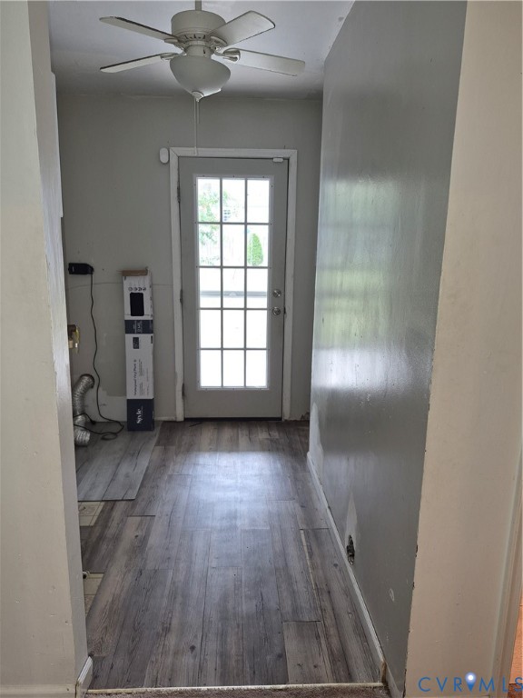 Wood-finish flooring with a multi-paneled door and an overhead ceiling fan