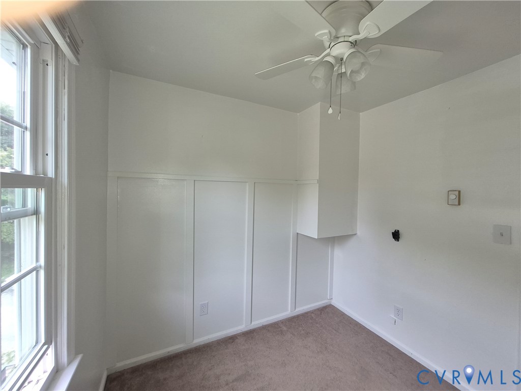 Room featuring board and batten paneling, ceiling fan with integrated lighting, and a double-hung window
