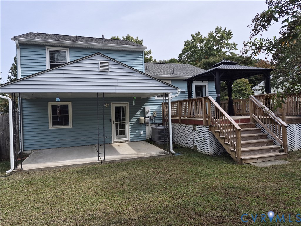 Expansive rear exterior featuring blue siding, a multi-level wood deck, an attached covered patio, and a standalone gazebo