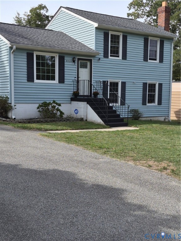 Blue siding exterior with contrasting dark shutters, dark roof, dark entry steps, and an asphalt driveway
