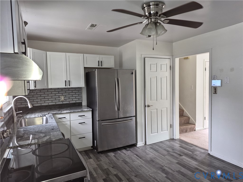 Kitchen featuring wood-finish flooring, white cabinetry with dark hardware, a stainless steel refrigerator, and dark countertops
