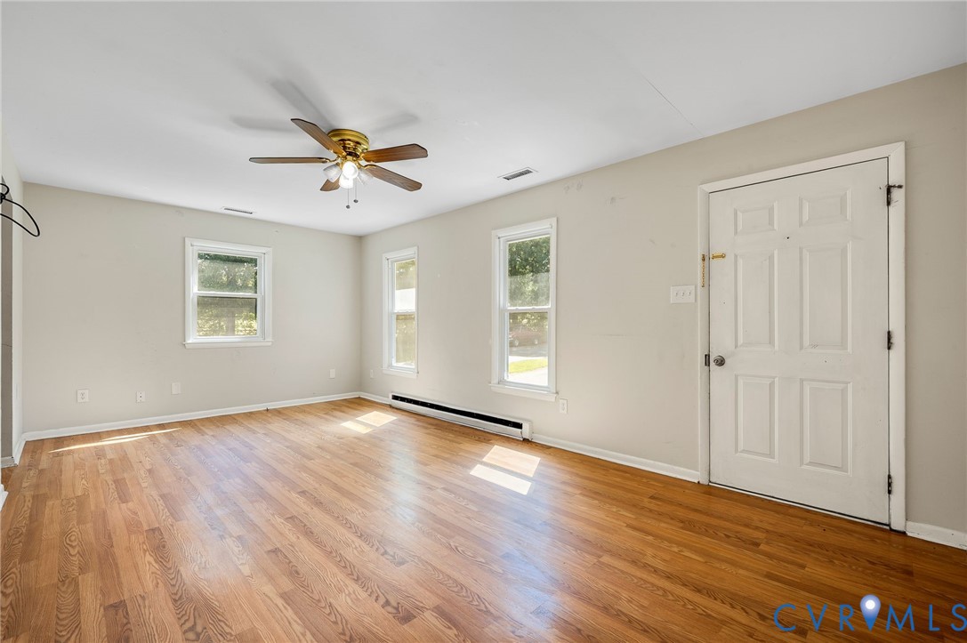 Hardwood flooring throughout, multiple windows, ceiling fan, and painted walls