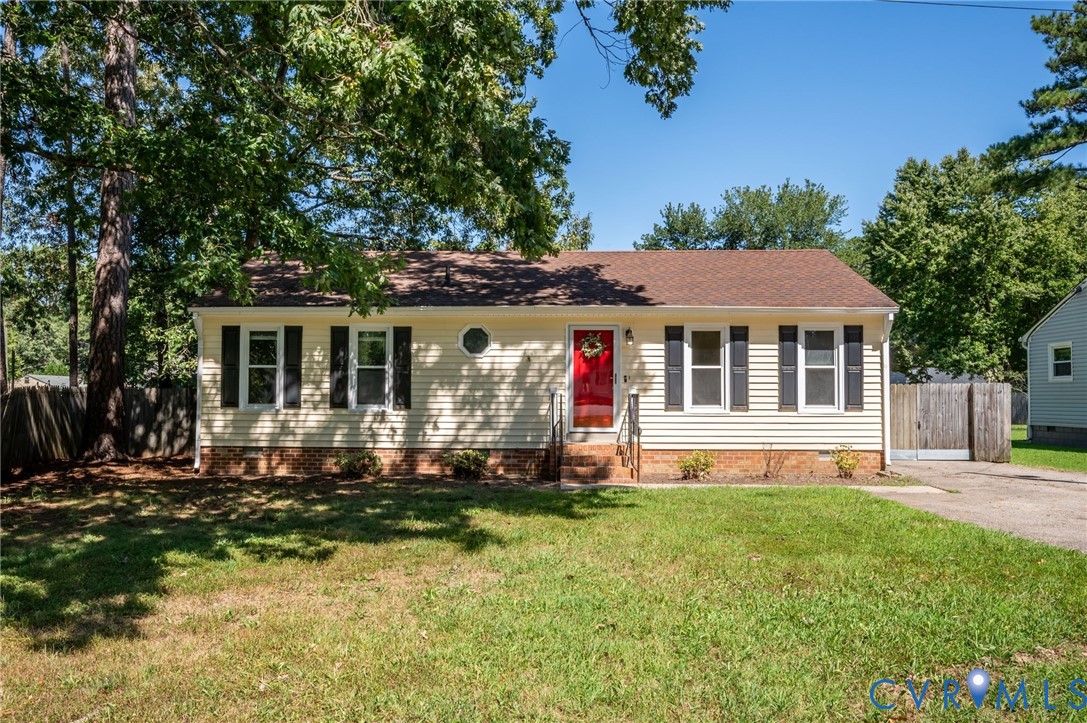 Yellow siding exterior with dark shutters, red front door, and a circular window Yellow siding exterior with dark shutters, red front door, and a circular window