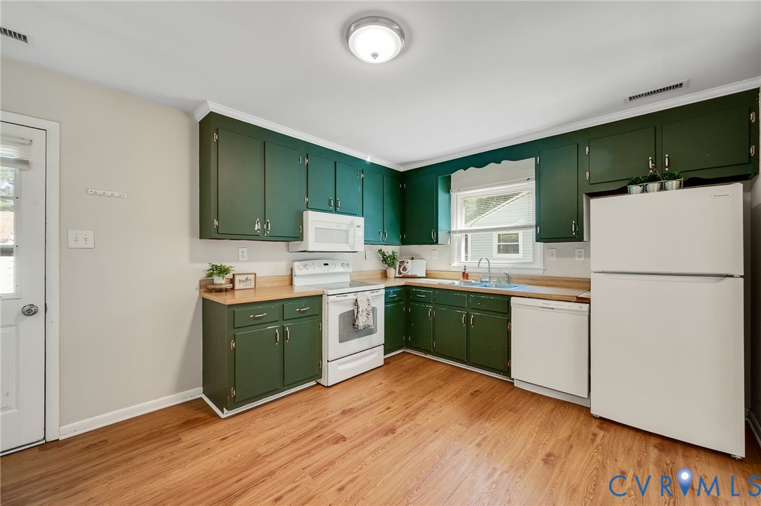 Kitchen featuring abundant green cabinetry, wood-finish countertops, and a full suite of white appliances including a refrigerator, range, and dishwasher
