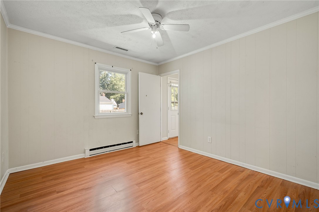 Wood-finish flooring, white paneled walls, ceiling fan, and window with exterior views