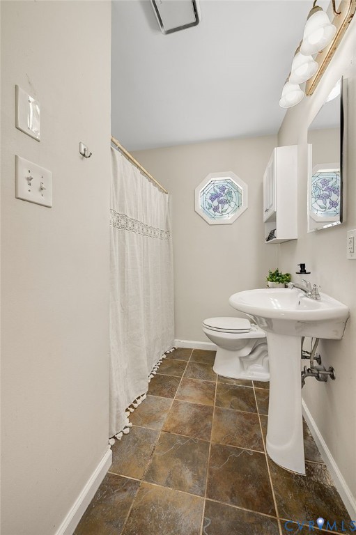 Pedestal sink, wall-mounted mirror, square tile flooring, decorative octagonal window, and wall-mounted storage cabinet