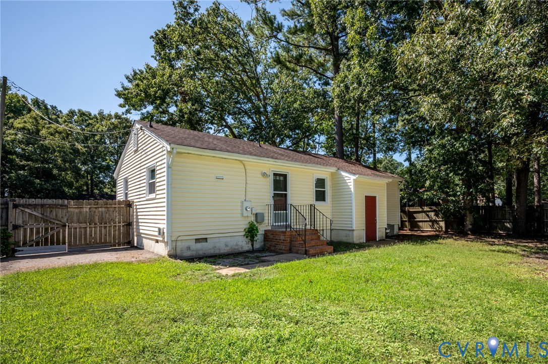 Yellow siding exterior with white trim, a brown shingle roof, and a red rear entry door