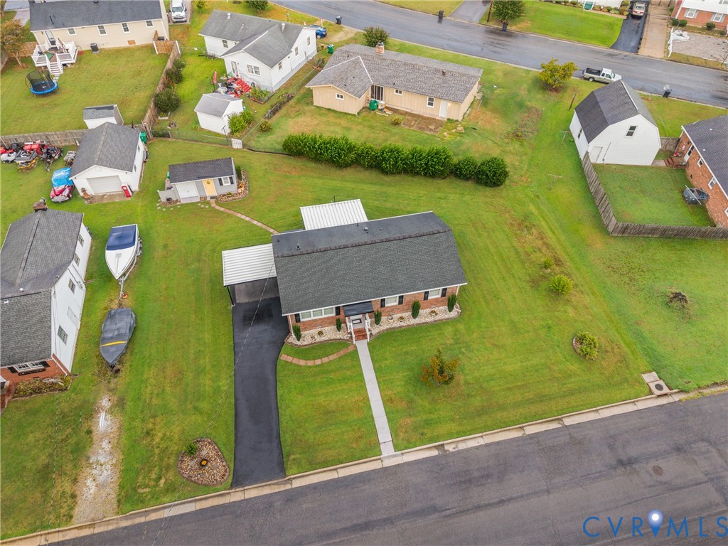 Brick exterior with a covered carport, paved driveway, and established front landscaping