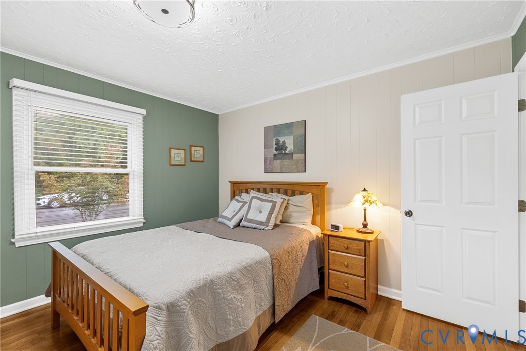 Hardwood flooring, painted paneled accent wall, white trim, and a six-panel interior door