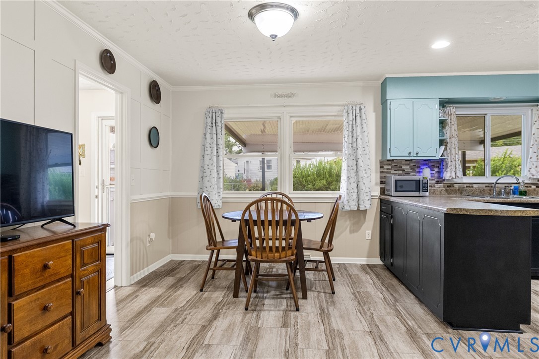 Eat-in kitchen featuring wood-finish flooring, two-tone cabinetry, a tile backsplash, and a double window
