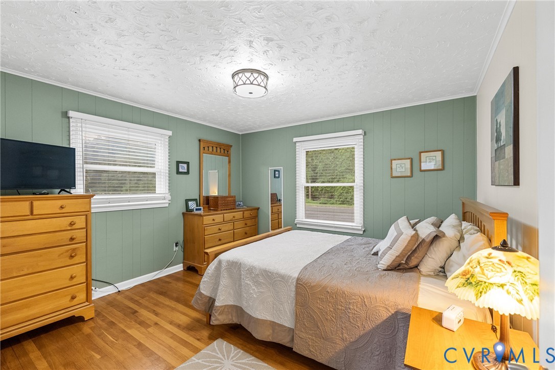 Hardwood flooring, painted paneled walls, ceiling-mounted light fixture, and multiple windows