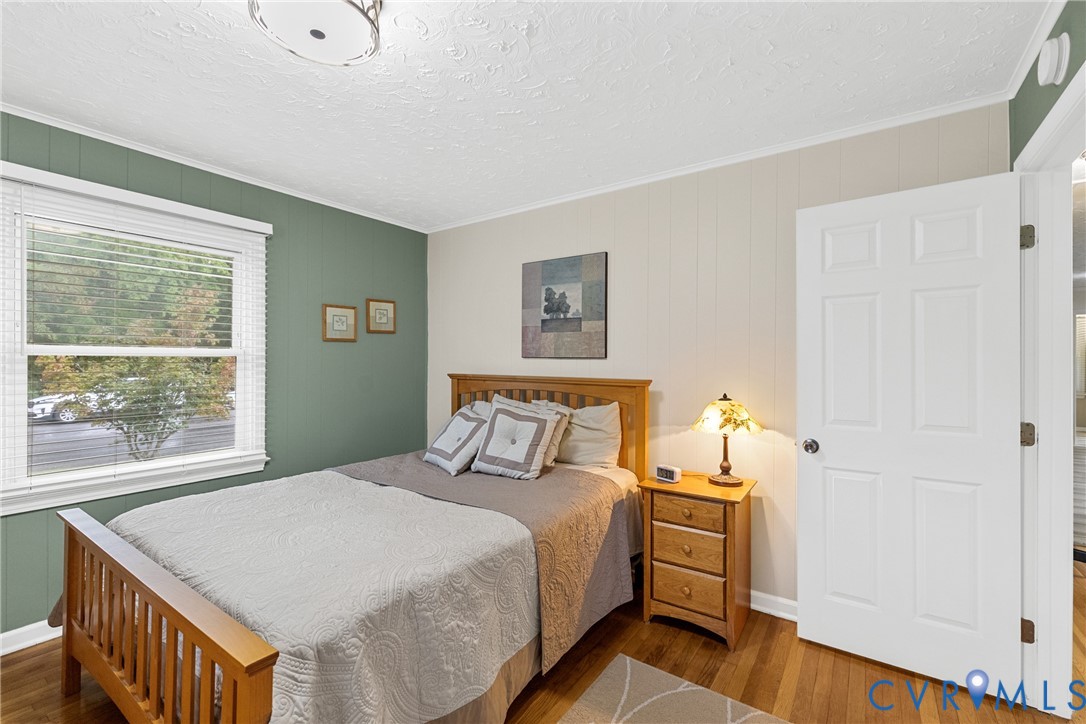 Hardwood flooring, painted paneled walls, white trim, and a ceiling-mounted light fixture