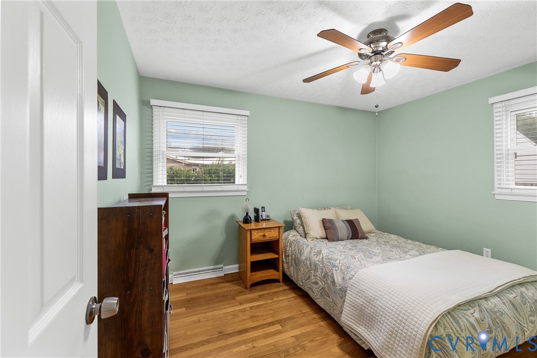 Wood-finish flooring with a ceiling fan light fixture and window with blinds
