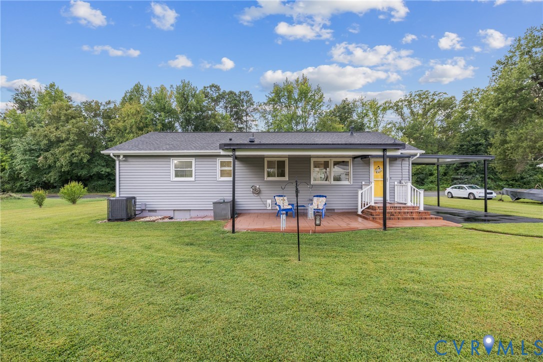 Expansive green lawn, wood-tone deck, attached covered patio, covered carport, and mature trees