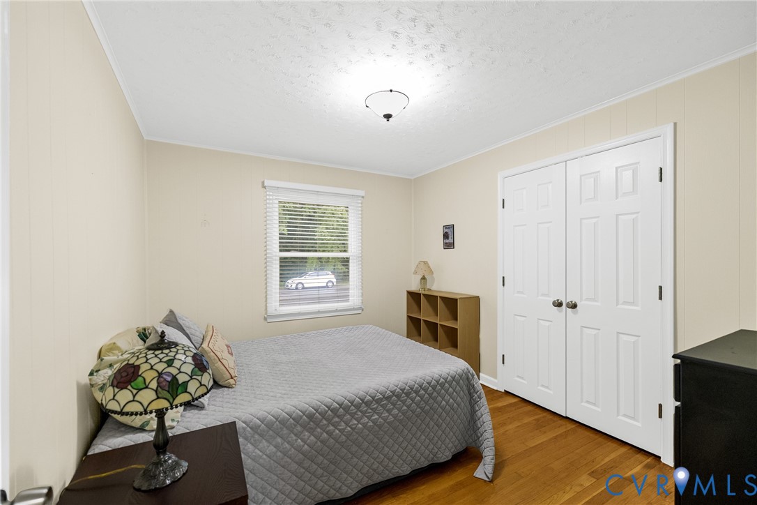 Wood-finish flooring, neutral wall paneling, and a ceiling-mounted light fixture