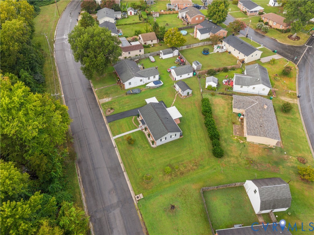 Aerial presentation of a residential property featuring a dark-shingle roof, white exterior siding, and a paved driveway