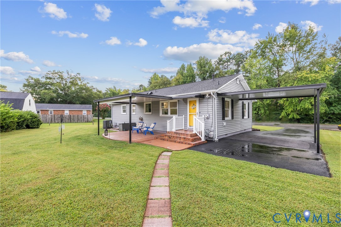 Spacious lawn with a paver pathway leading to a brick patio