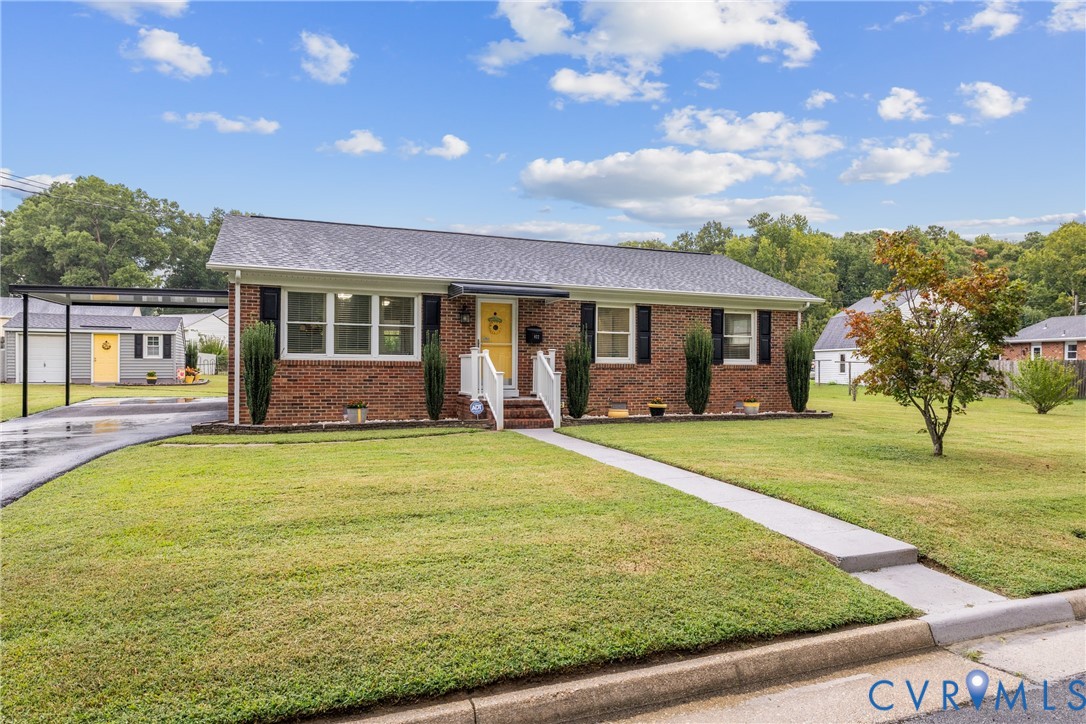Brick facade, front lawn, carport, paved driveway, and sidewalk