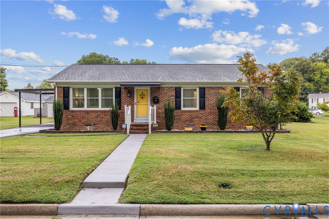 Brick exterior with a gray shingle roof and a vibrant yellow front door