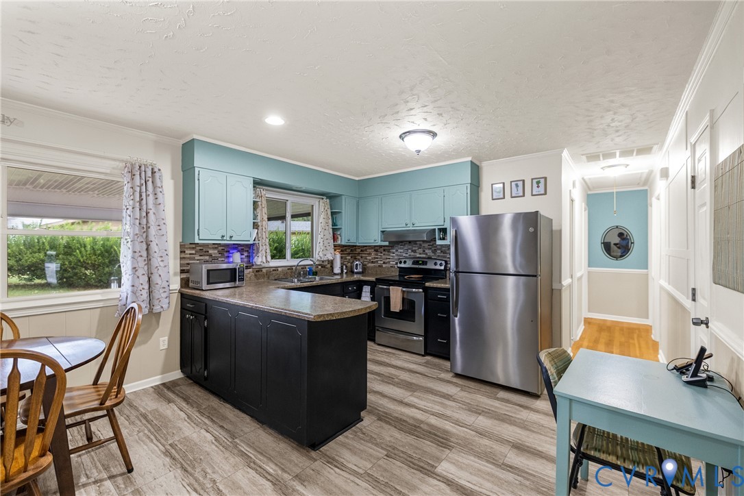 Kitchen featuring blue upper cabinetry, a dark-toned island with countertop, stainless steel refrigerator, and wood-finish flooring