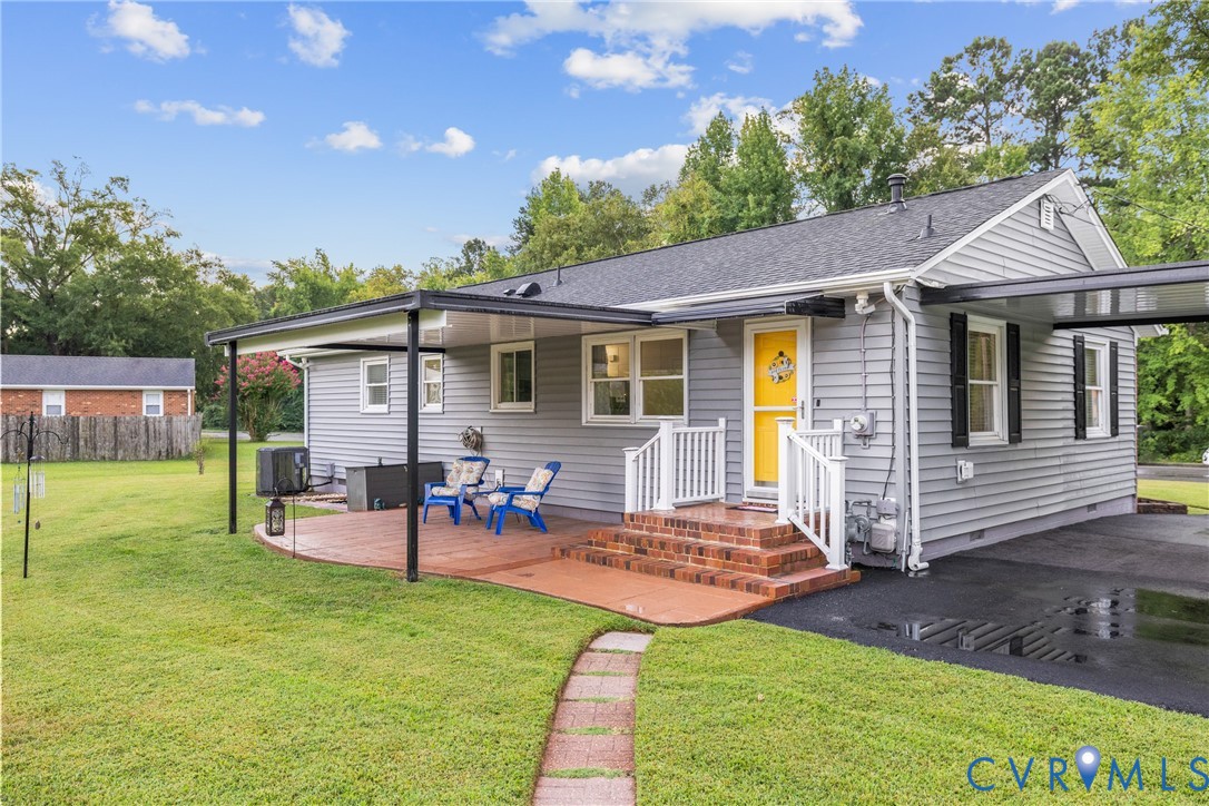 Siding exterior with a covered patio, brick steps, and a paved driveway