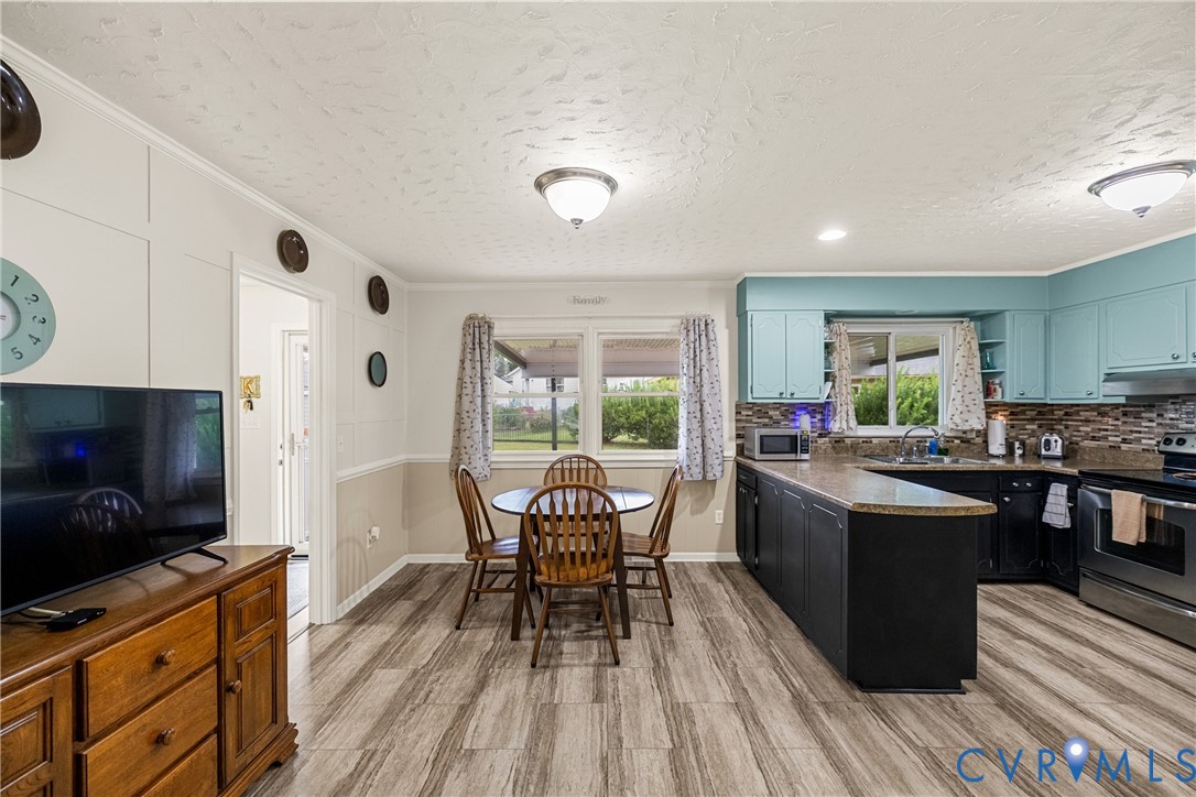 Kitchen featuring wood-finish flooring, two-tone cabinetry, stainless steel appliances, a multi-tone tile backsplash, and recessed lighting