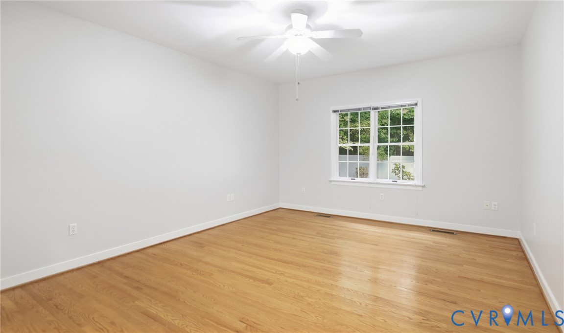 Hardwood flooring, white walls, white trim, single window, and a ceiling fan with light fixture