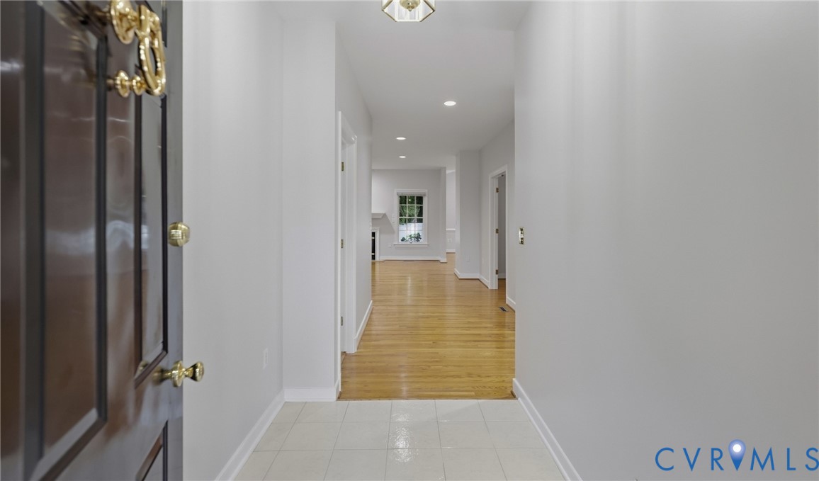Foyer entry with tile flooring, dark wood-finish door, and brass-tone hardware Foyer entry with tile flooring, dark wood-finish door, and brass-tone hardware