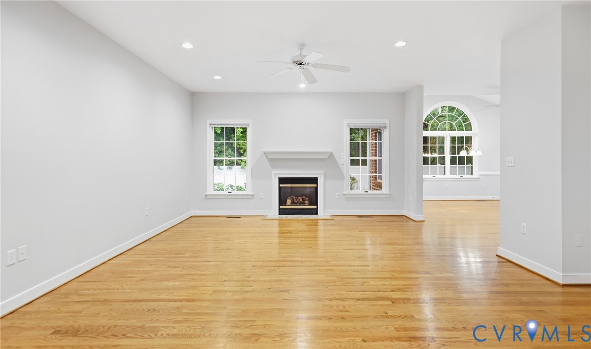 Hardwood flooring throughout, recessed lighting, ceiling fan, and a fireplace with a mantel