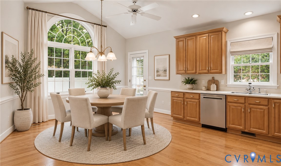 Arched window with transom details, vaulted ceiling, wood-finish flooring, wood cabinetry, and stainless steel appliances