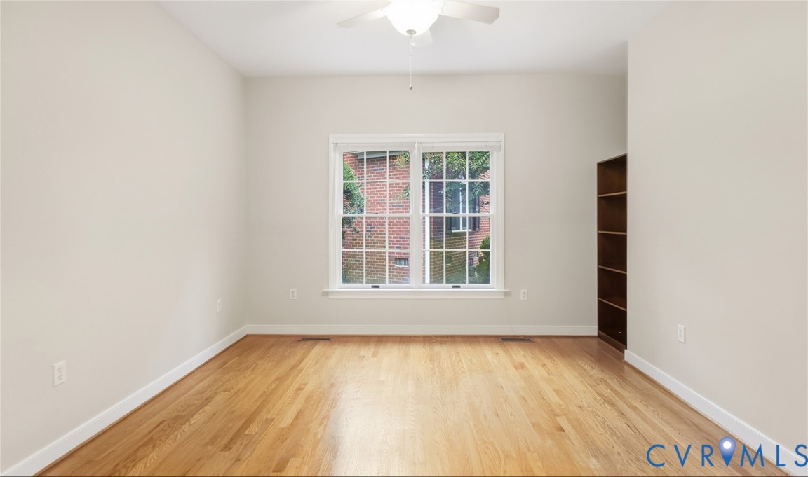Hardwood flooring, white trim, white walls, built-in shelving, and a ceiling fan