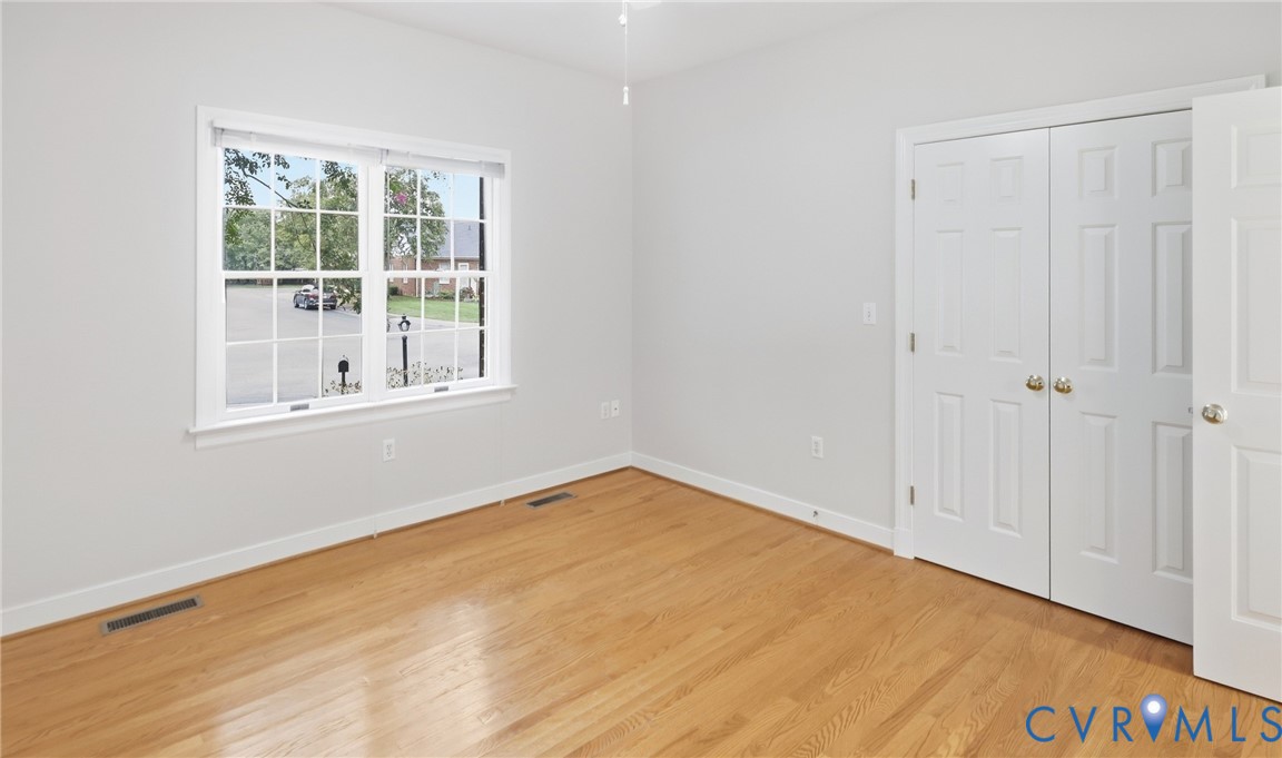 Hardwood flooring, painted interior walls, white trim, white paneled doors, and a double-hung window