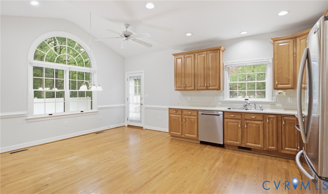 Vaulted ceiling, arched window, wood-finish flooring, wood cabinetry, stainless steel appliances