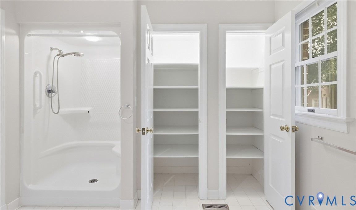 Built-in shower with integrated seating, dual storage closets with shelving, and a multi-pane window
