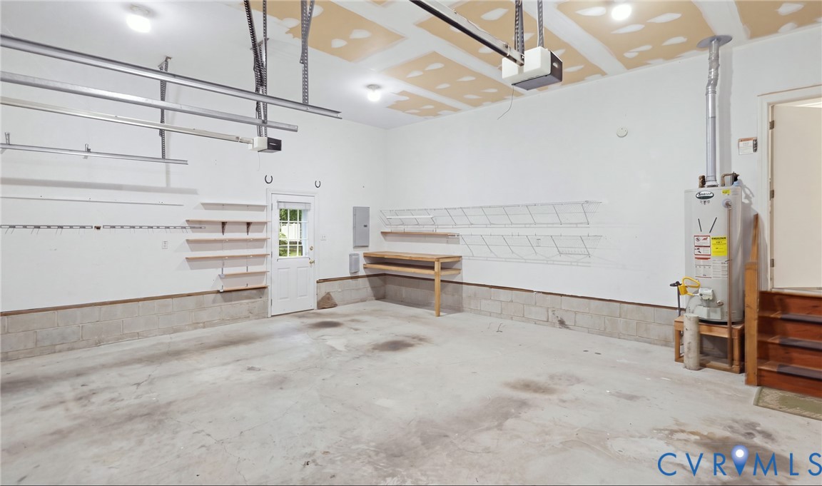 Concrete flooring garage with wall-mounted shelving, built-in workbench, and overhead lighting