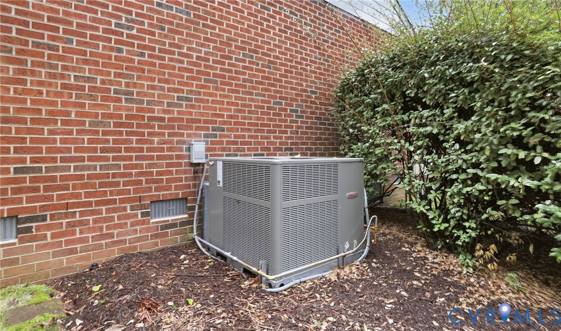 Brick exterior with a ground-mounted HVAC unit and surrounding landscaping