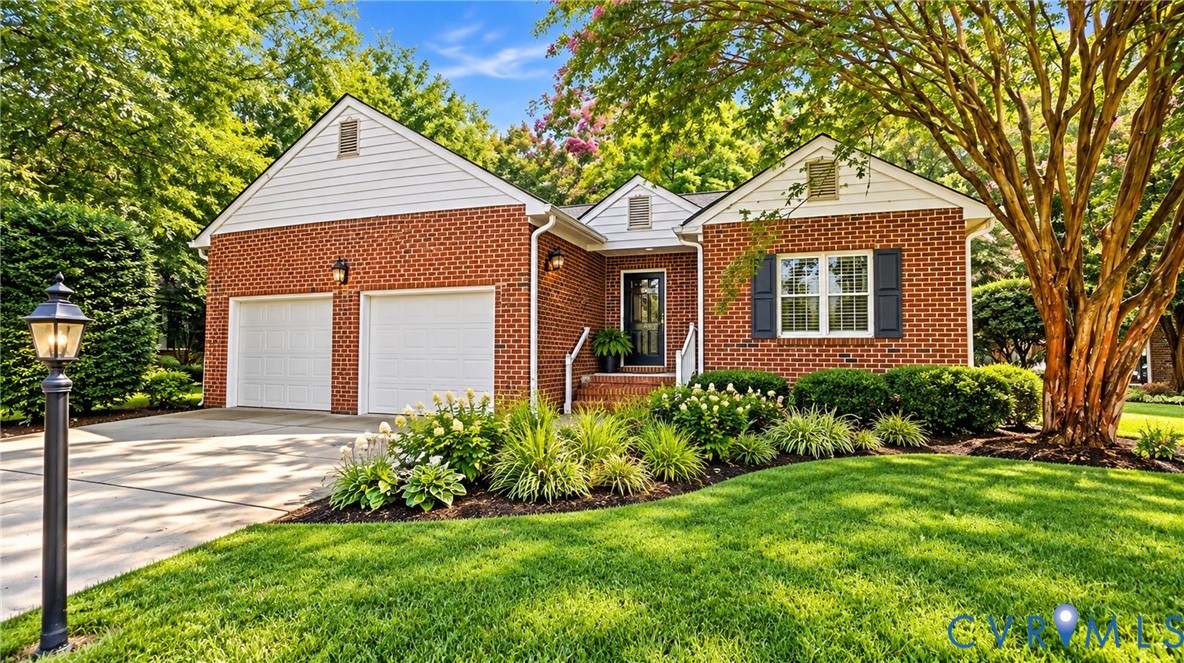 Brick exterior with white gables, two-car garage, front entry porch, mature landscaping, and an exterior lighting fixture