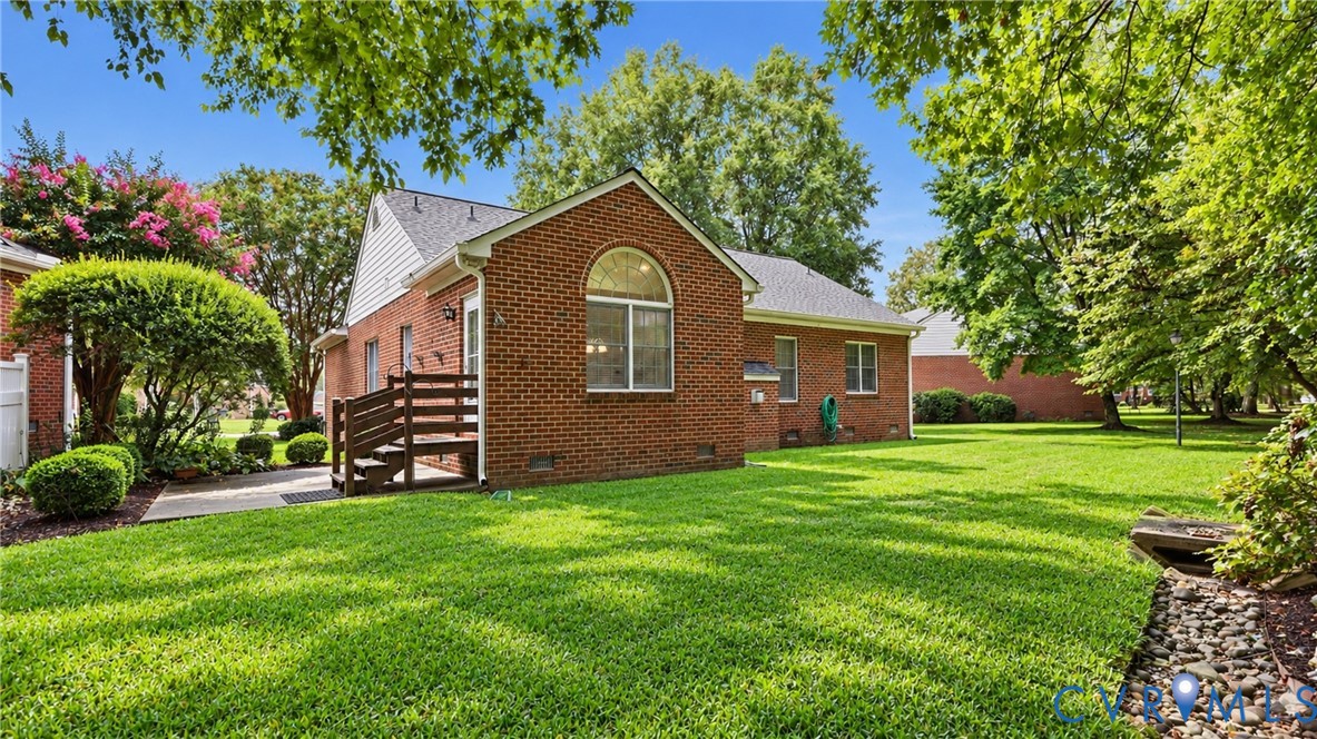 Brick exterior with an arched window, private rear patio, and a wood deck with stairs Brick exterior with an arched window, private rear patio, and a wood deck with stairs