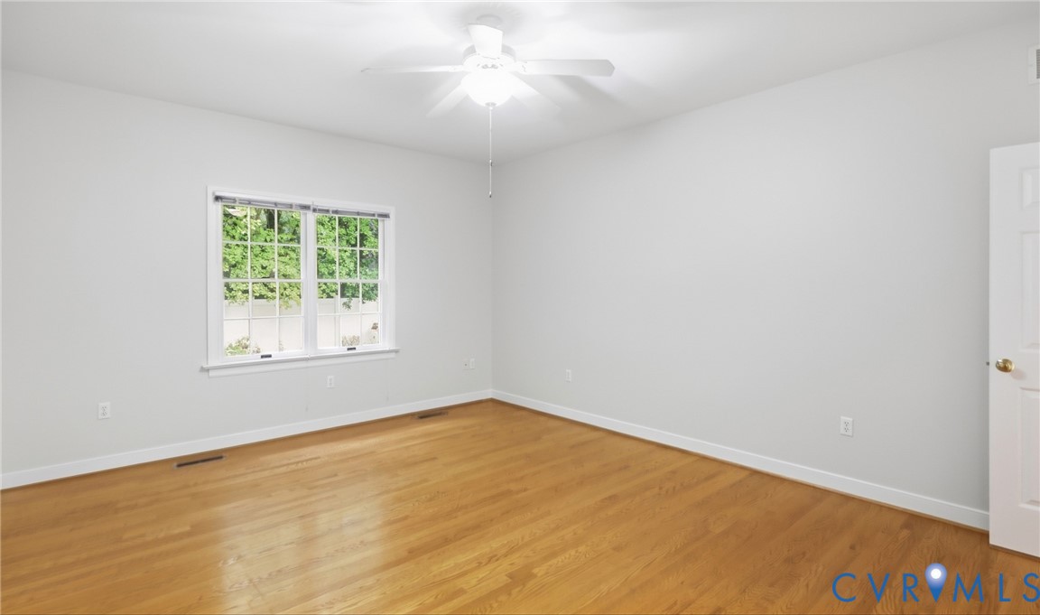 Hardwood-style flooring, white walls, and a ceiling fan with light fixture