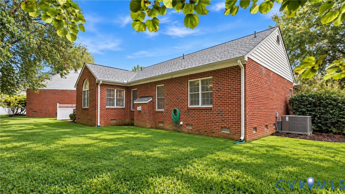 Brick exterior with white trim, white vinyl fencing, and a manicured lawn Brick exterior with white trim, white vinyl fencing, and a manicured lawn