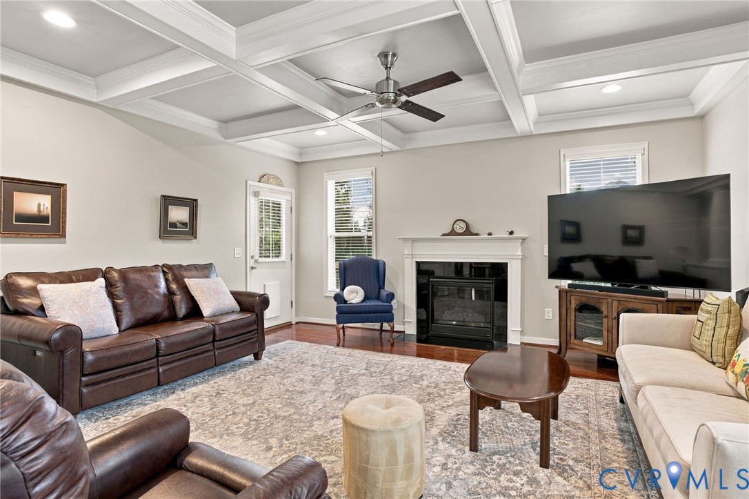 Coffered ceiling with recessed lighting, wood-finish flooring, white mantel fireplace, and a door with glass panelling