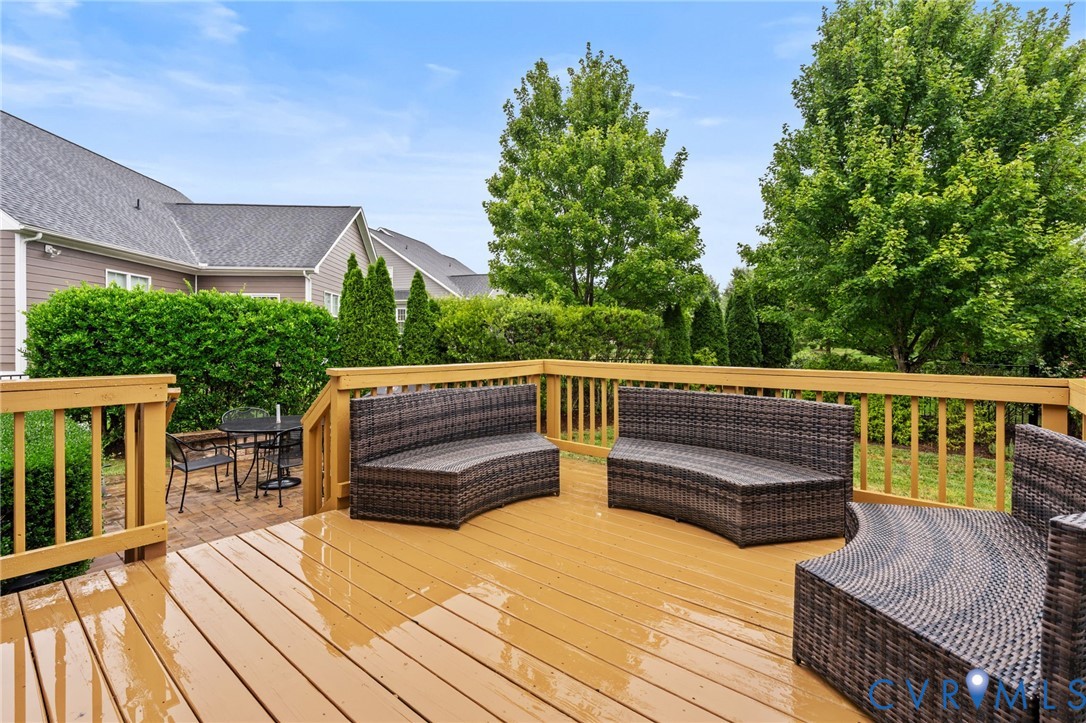 Expansive wooden deck with railing, featuring a brick patio area