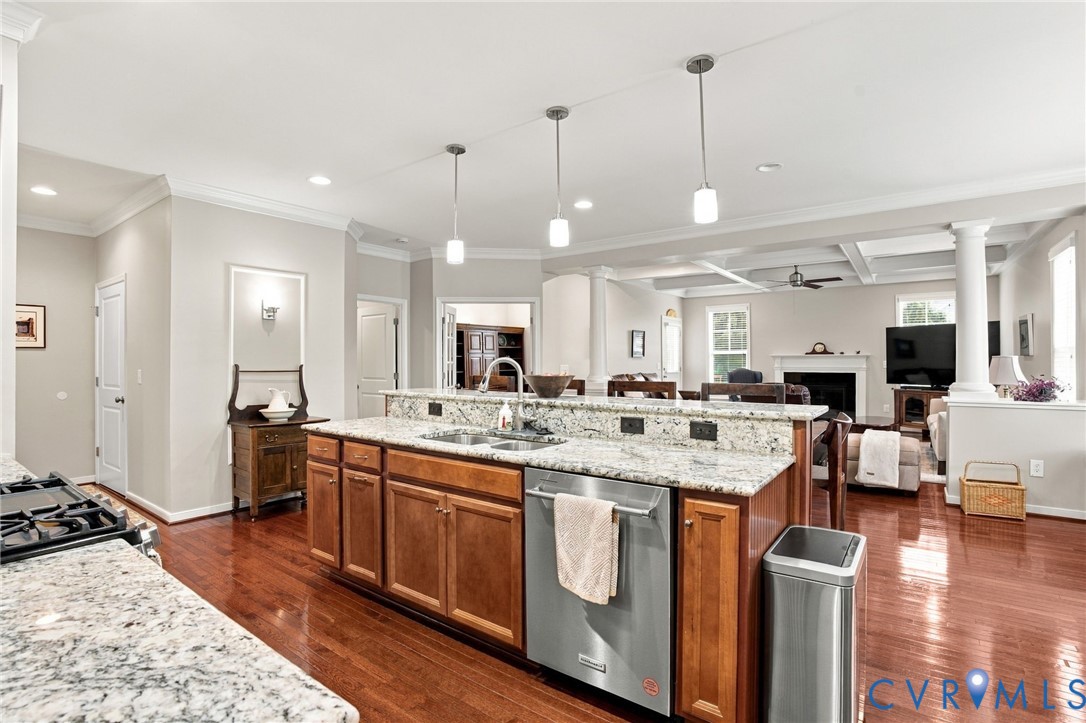 Open-concept kitchen featuring granite countertops, cherry wood-finish cabinetry, stainless steel appliances, and pendant lighting
